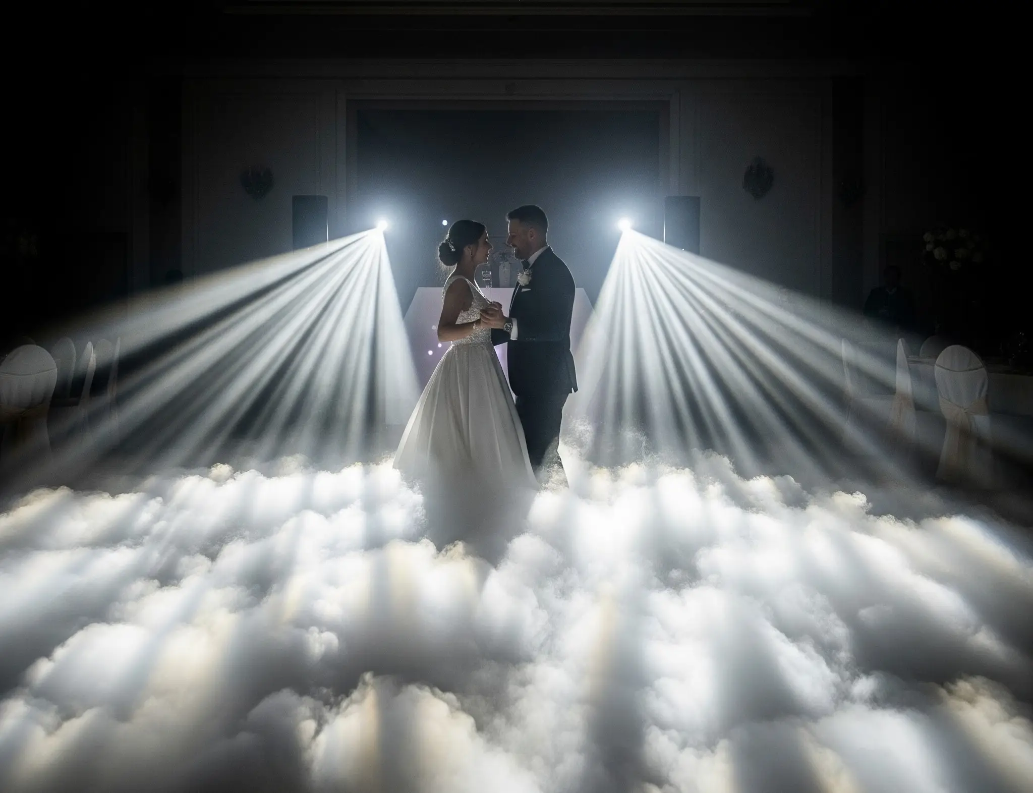 Novios bailando entre nubes de humo iluminadas por focos